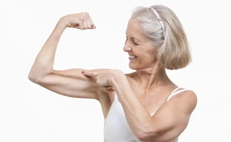 Older woman flexing and pointing at her bicep